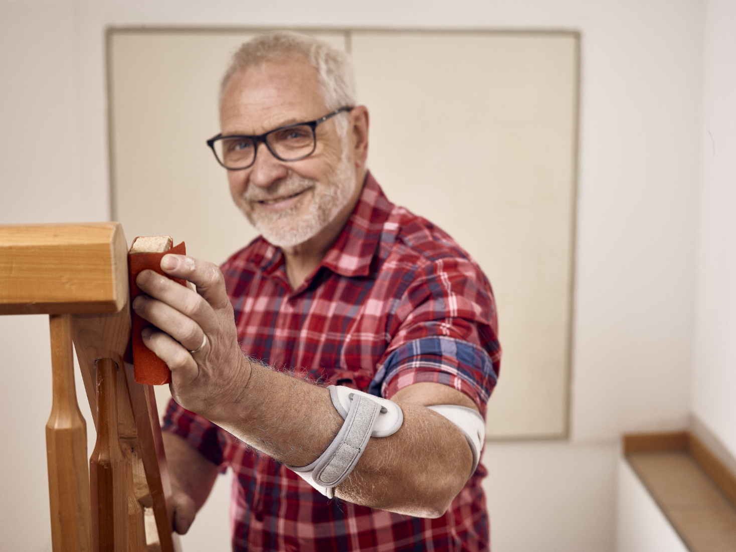 The Masalo Cuff – work pain-free with epicondylitis Elderly man wearing the Masalo cuff sanding a banister
